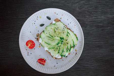 Frisches Vollkornbrot mit körnigem Frischkäse, Gurke & Tomate