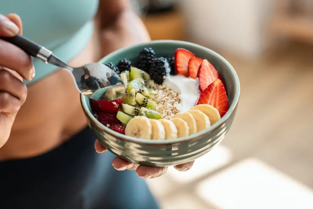 Nahaufnahme einer gesunden Frühstücksbowl mit Joghurt, Haferflocken, frischen Beeren, Kiwi und Bananenscheiben – perfekt vor dem Training.
