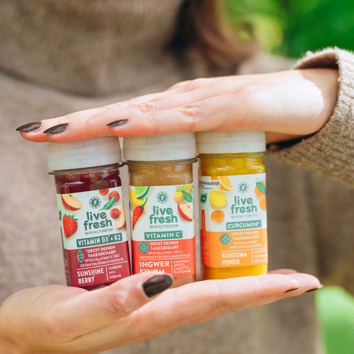 Eine Person hält drei LiveFresh-Shots in drei verschiedenen Geschmacksrichtungen in den Händen. Der Kopf ist nicht zu sehen. 