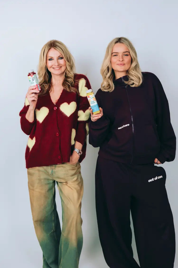 Frauke & Nele Ludowig mit Säften von LIveFresh in der Hand vor einer weißen Wand. 