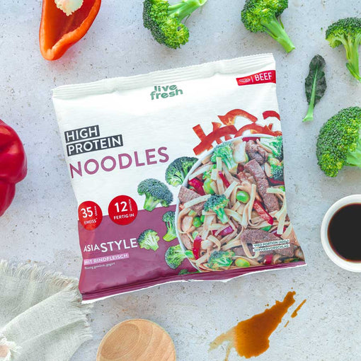 Das erste Bild zeigt eine Packung „Live Fresh High Protein Noodles“ in der Geschmacksrichtung Asia Style mit Rindfleisch. Die Verpackung hebt den Proteingehalt von 35 g und die Zubereitungszeit von 12 Minuten hervor. Im Hintergrund sind frische Zutaten wie Brokkoli, Paprika, und Sojasauce zu sehen, was die asiatische Inspiration unterstreicht.