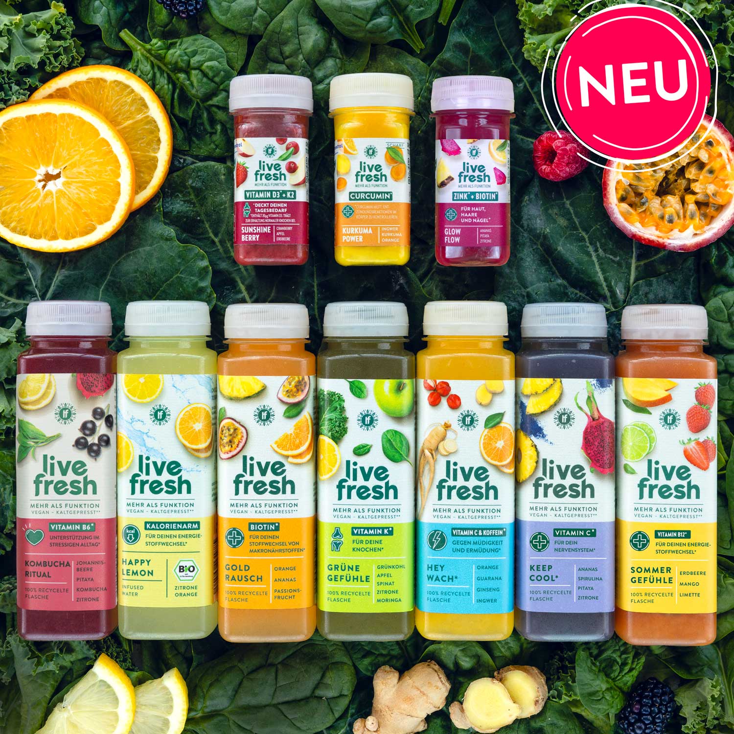 7 verschiedene Säfte und 3 Shots von LiveFresh, im Hintergrund sind Spinat- und Kohlblätter zu sehen wie andere Früchte. Rechts oben ist ein Hinweis mit "NEU" zu sehen. 