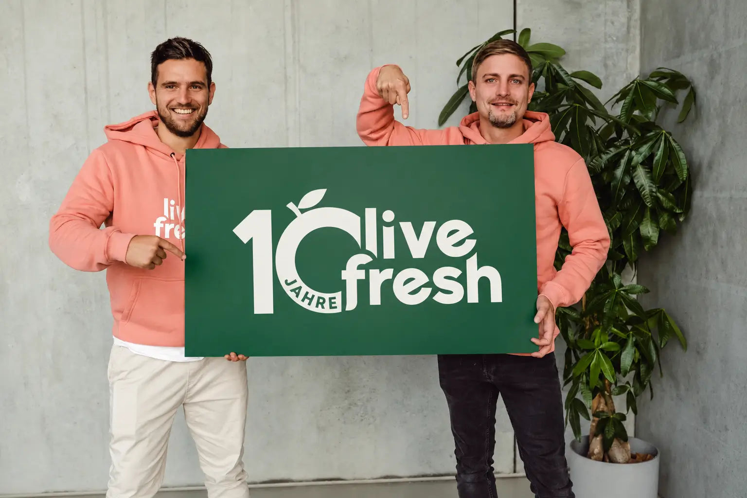 Simon und Bene, die Gründer von LiveFresh, halten ein Schild mit dem 10-Jahre-Logo